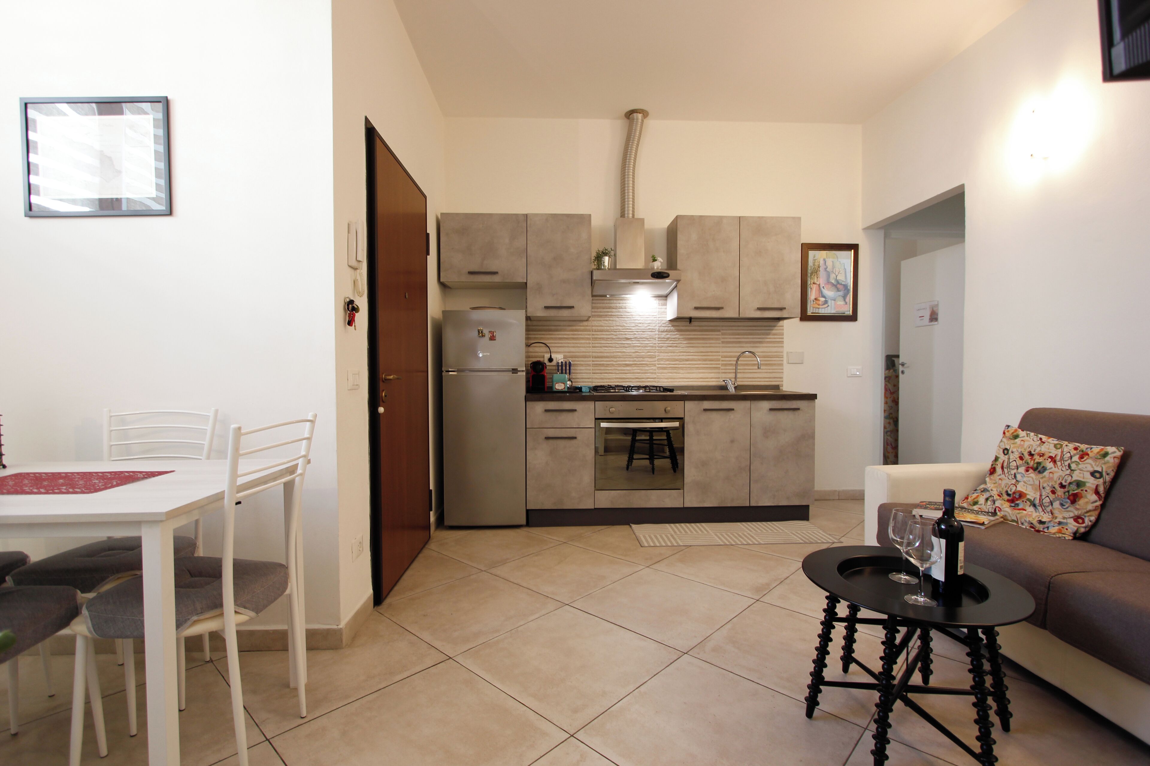 A compact kitchen with modern appliances, a dining area with a table and chairs, and a living area with a sofa and a small coffee table.