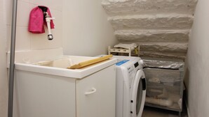A laundry area with a washing machine, a mop, and a pink towel hanging on the wall. - Suite dei Vanni - Free private parking (Florence)