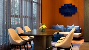 A modern dining area with a round table, four chairs, a blue decorative wall piece, and a sofa with blue cushions. - Hampton by Hilton (Pingxiang)