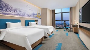 A hotel room with two beds, a desk, a TV, and a large window with a city view. - Hampton by Hilton (Pingxiang)