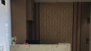 Ένας σύγχρονος χώρος υποδοχής με έναν μαρμάρινο πάγκο, ένα φυτό σε γλάστρα και έναν τοίχο με διακοσμητικό σχέδιο.