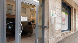 A building entrance with a car parked in front, a door with a handle, and a window with a view of a balcony. - Apartment 'Casa Giuseppe Centro - Sanremo' with Sea View near Piazza Colombo (Sanremo)