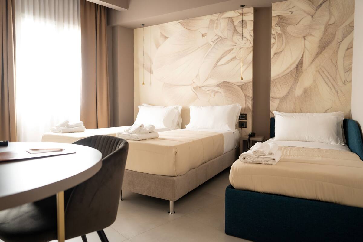 Une chambre d’hôtel avec deux lits, une table ronde et une chaise.