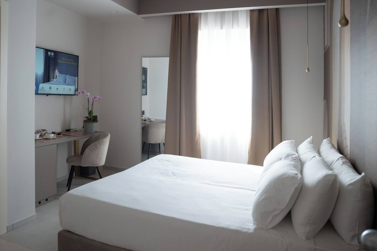Une chambre d’hôtel moderne équipée d’un lit, d’un bureau, d’une chaise et d’un téléviseur affichant un message.