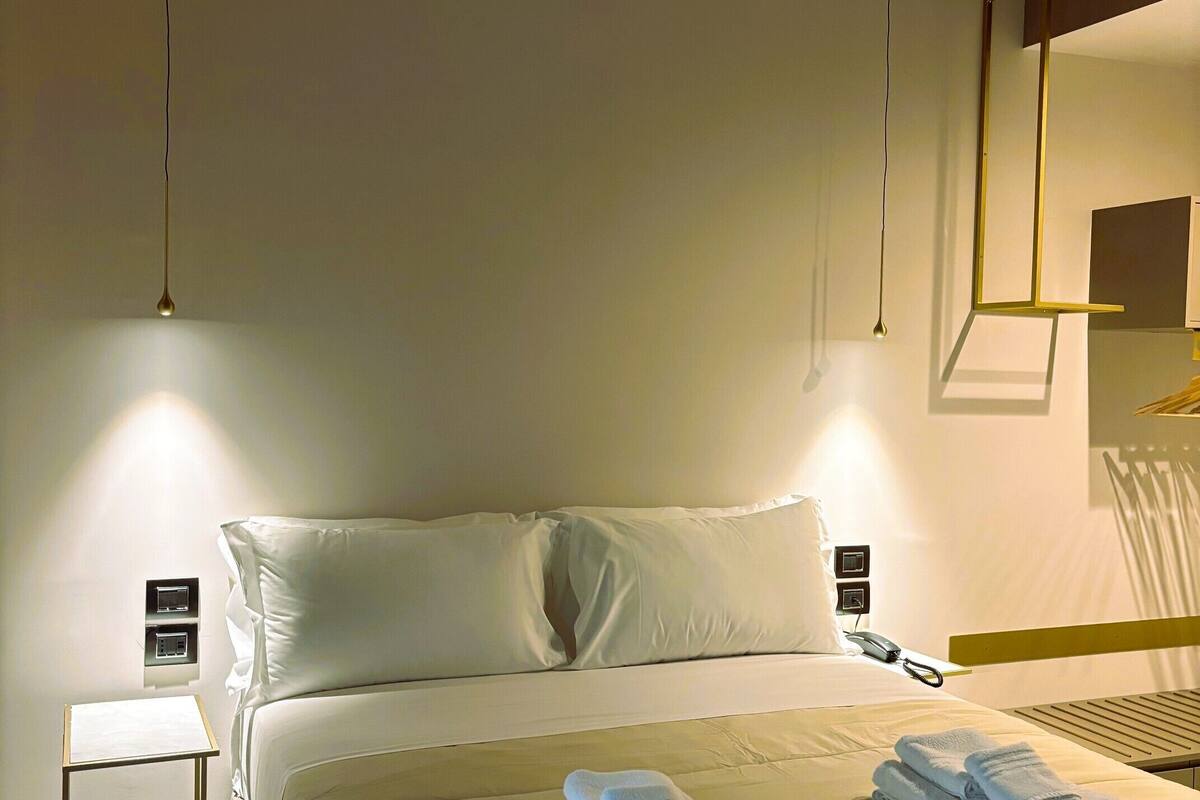 Une chambre d’hôtel avec un lit bien fait, des tables de chevet, un téléphone sur la table de chevet et un miroir fixé au mur.