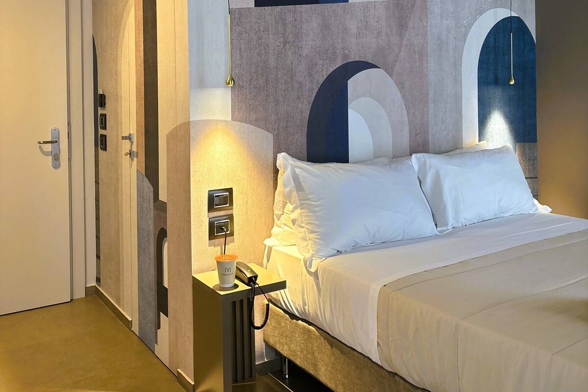 Une chambre d’hôtel avec un lit, une table de chevet et un mur orné de motifs géométriques.