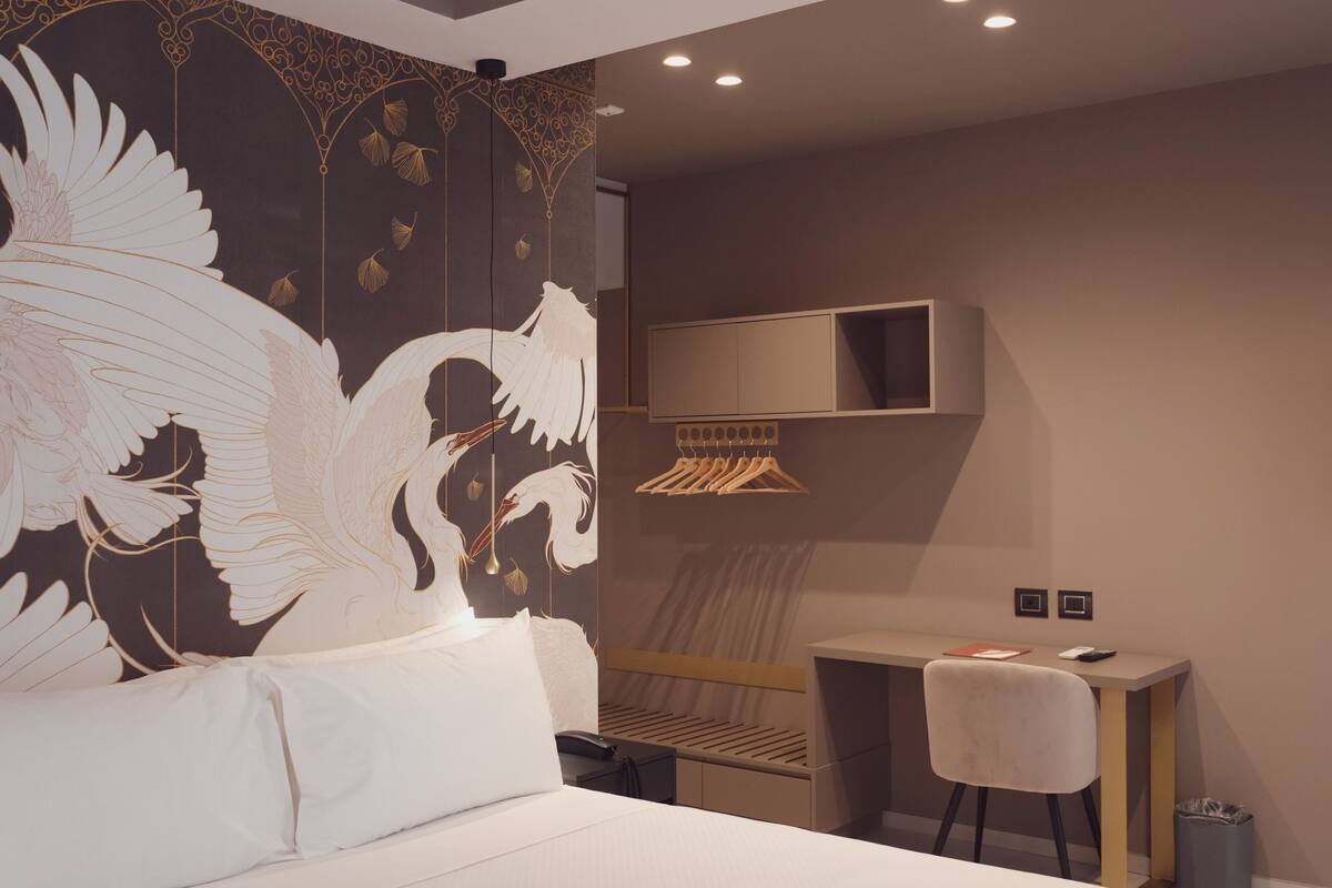 Une chambre d’hôtel avec un grand lit, un bureau, une chaise, une armoire et un téléviseur.