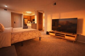 A bedroom with a bed, a TV, and a kitchenette in the background. - MDR 1BA ESCAPE (Marina del Rey)