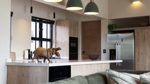Uma cozinha moderna com ilha de madeira, luminárias pendentes, geladeira de aço inoxidável e uma janela ampla.