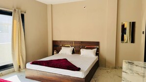 Una camera d'albergo con un letto grande, una testiera in legno, un comodino e una finestra con tende.