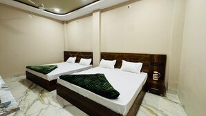 Camera d'albergo con due letti, pavimento in marmo, testiera in legno e comodino con una tazza e una cornice.