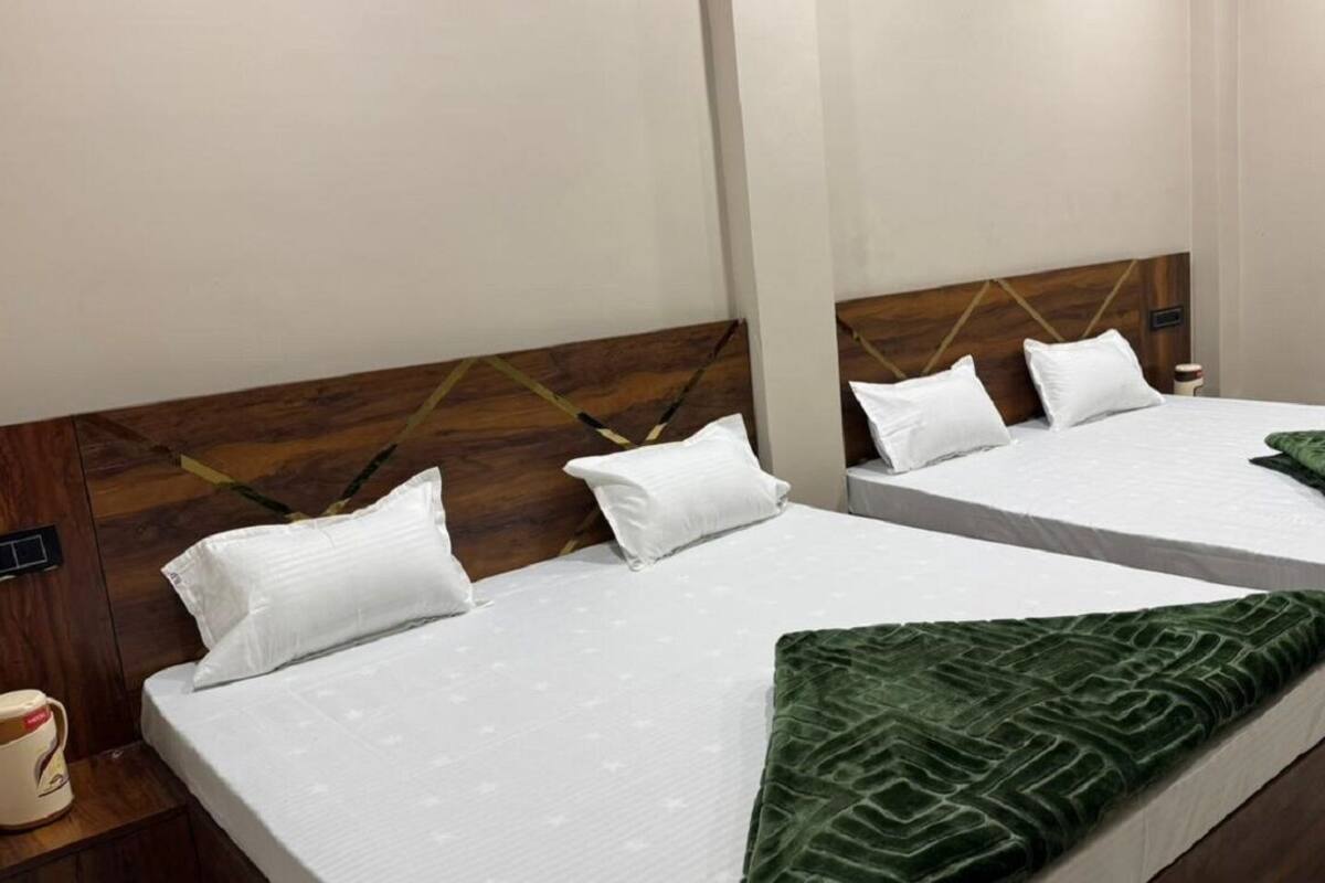 Twee éénpersoonsbedden met houten hoofdborden, witte beddengoed en een groene plaids.