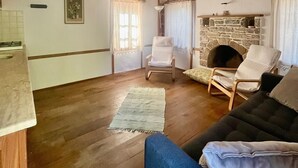 A rustic living room with wooden beams, a stone fireplace, and a cozy seating area. - Zeytin Evi (Datca)