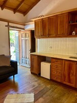 Eine kompakte Küche mit Holzschränken, einer gefliesten Spritzschutzwand und einem integrierten Geschirrspüler.