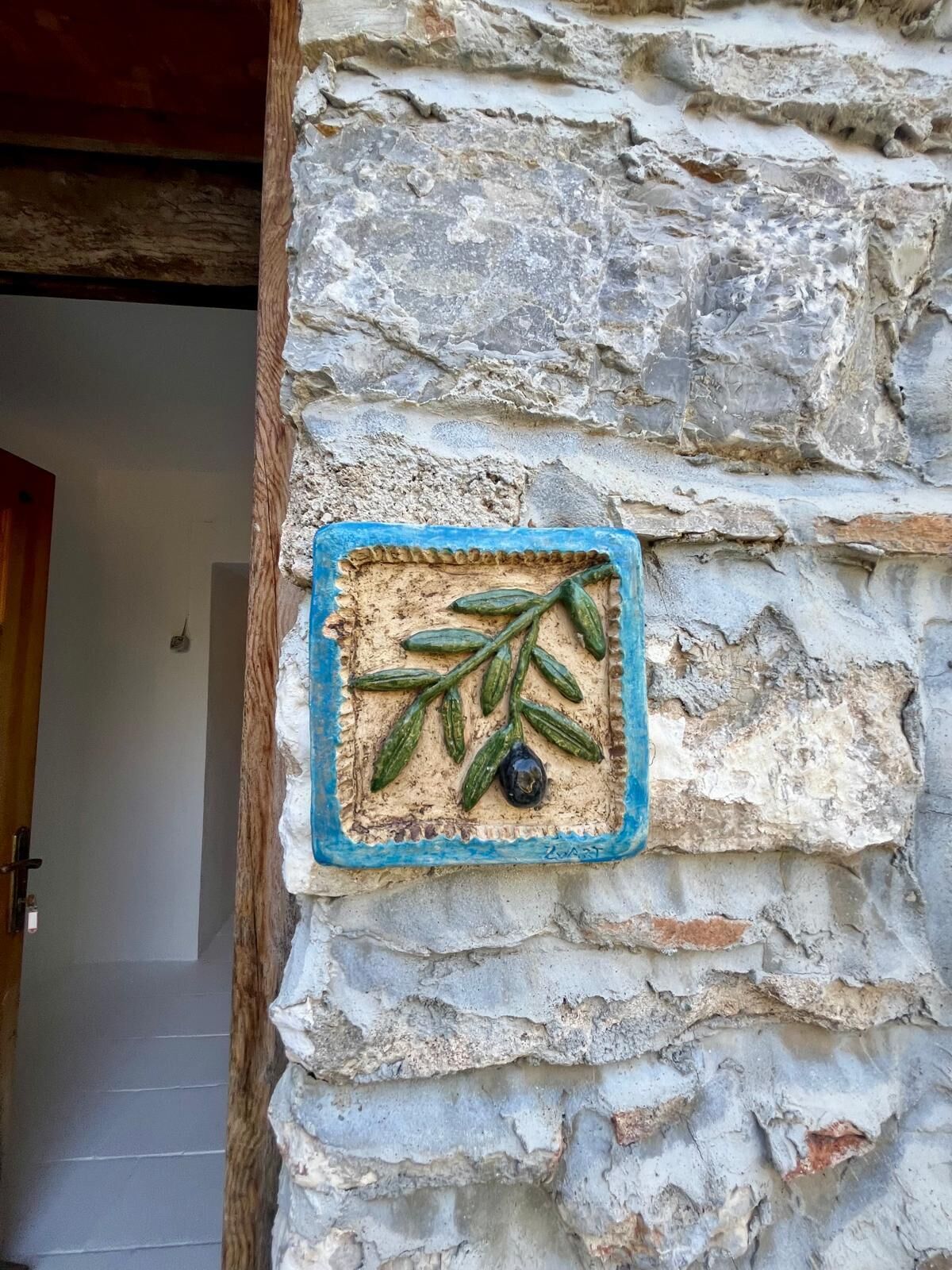 A stone wall with a decorative carving of a plant and a black object.