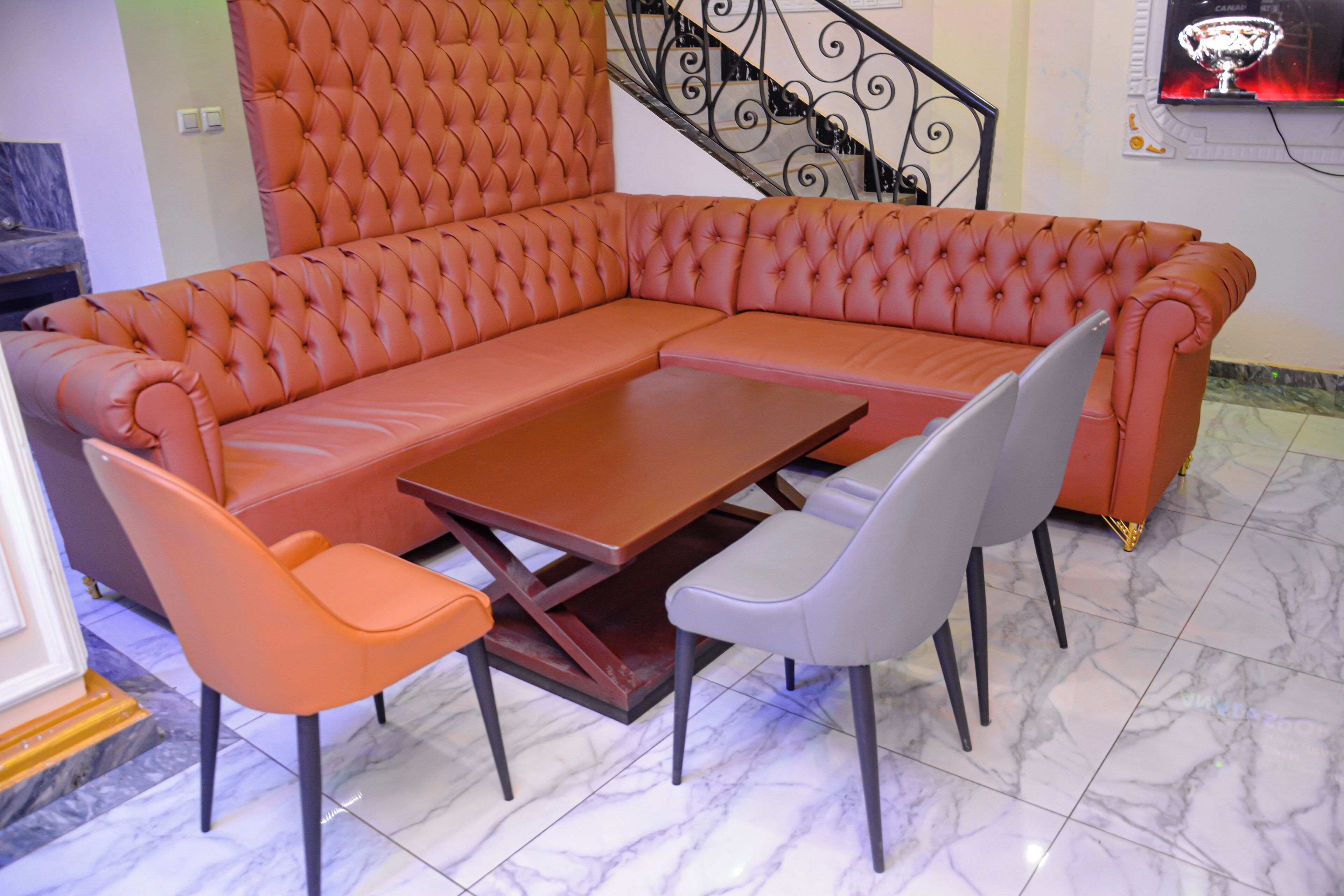 Een modulaire bank met een passende voetenbankje, een houten salontafel en twee stoelen.