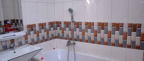 Un baño con una bañera blanca, un cabezal de ducha y un pared de azulejos con un diseño geométrico.