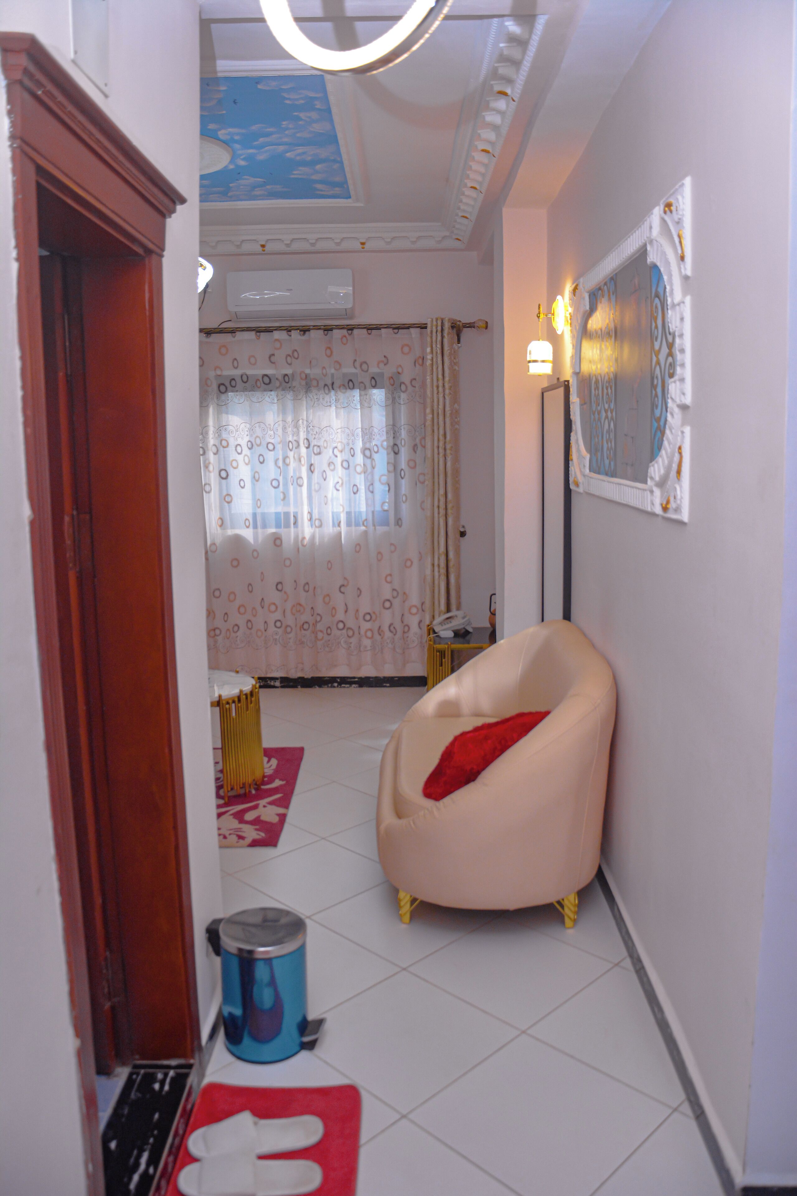 A room with a chair, a radiator, a trash bin, and a patterned curtain.