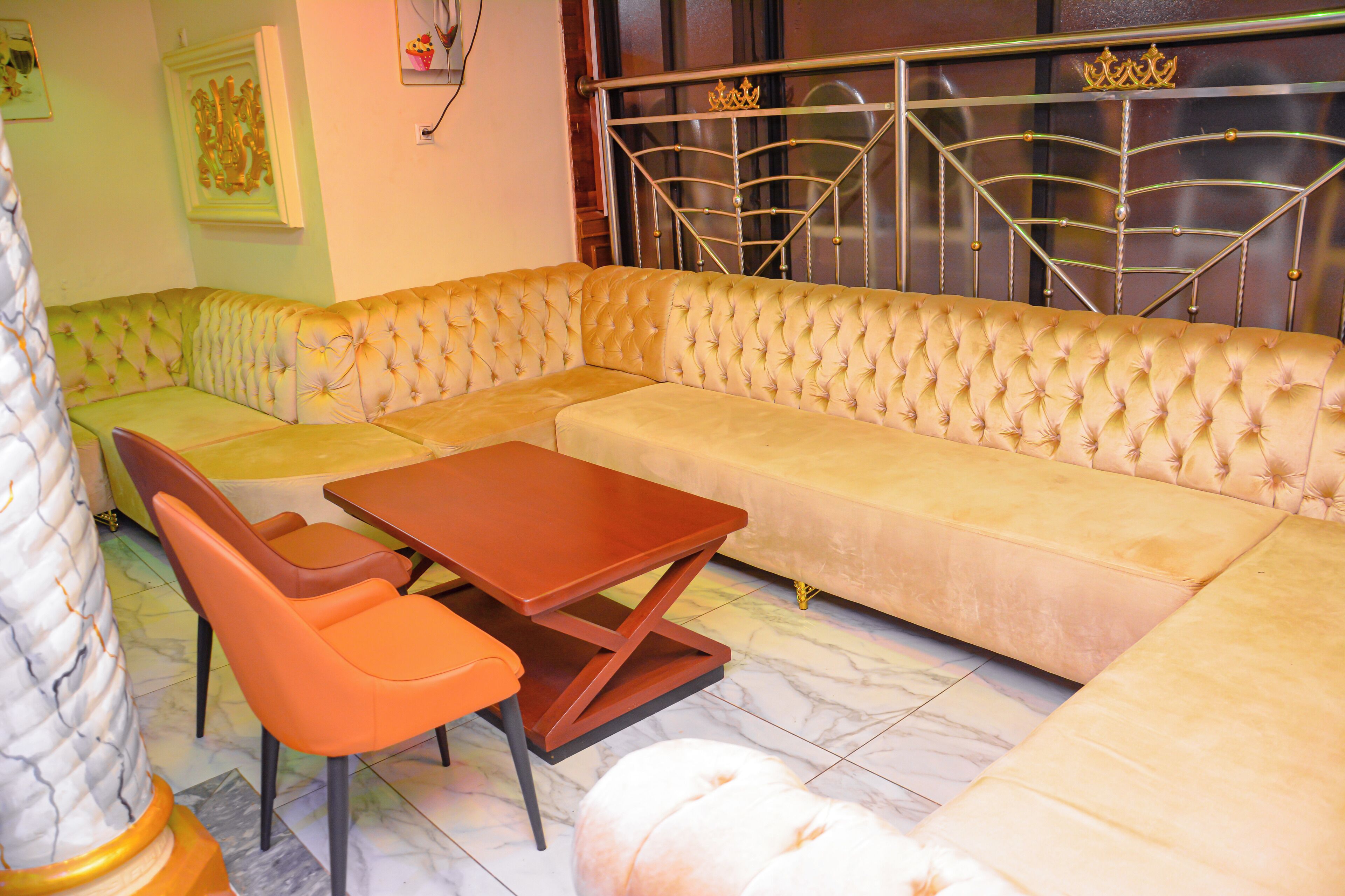 A living room with a large L-shaped sofa, a wooden coffee table, and two orange chairs.