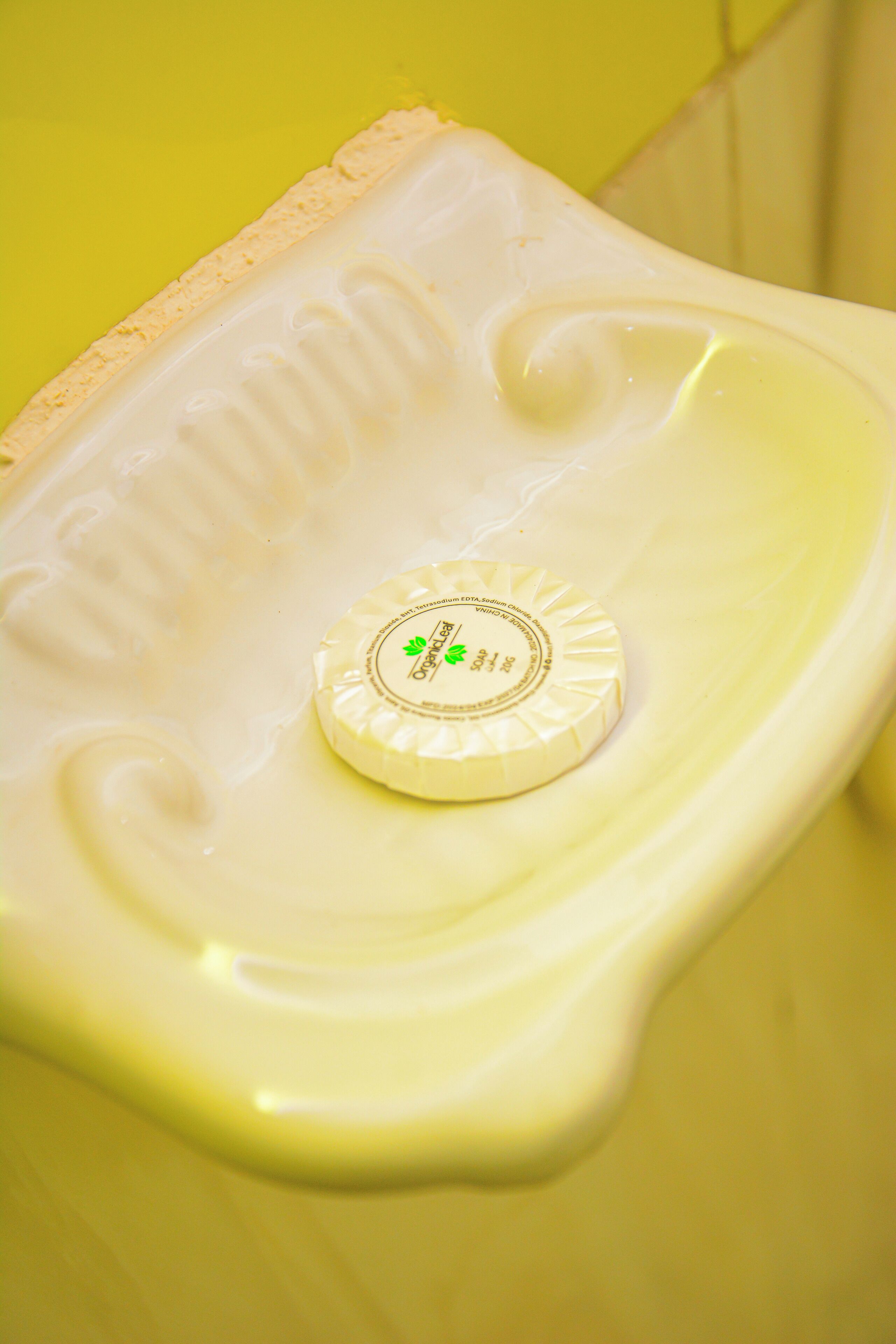 A toilet with a soap dispenser on the rim.