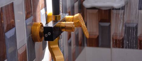 A shower with a yellow faucet and a soap dish.
