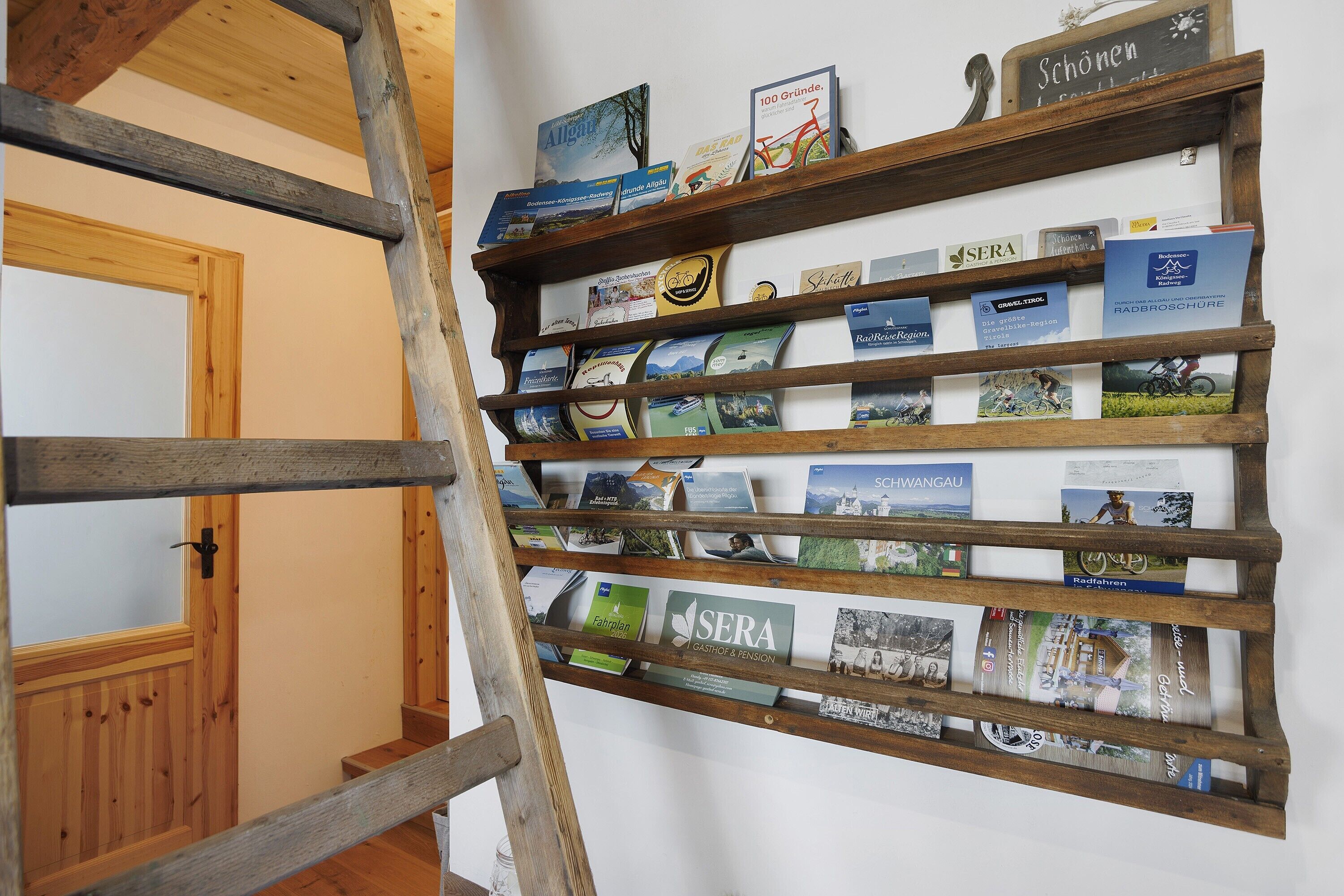 A wooden bookshelf with travel brochures and books.