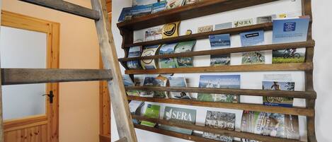 A wooden bookshelf with travel brochures and books.