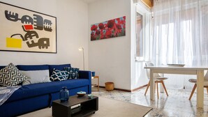 Un soggiorno con un divano blu, un tavolino, un quadro e una zona pranzo con tavolo e sedie.