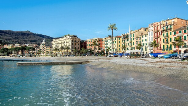 Un pittoresco paese costiero con edifici colorati, una spiaggia e acque cristalline.