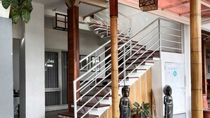 A staircase with a metal railing leading to an upper level. There are two statues on the ground floor. - Lacasa Senggigi By Royal Amreetha (Senggigi)