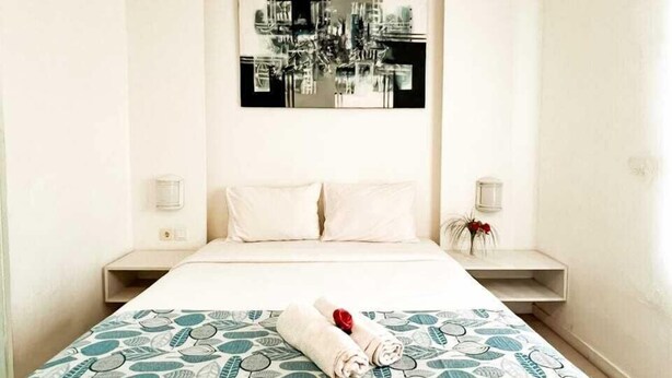 A hotel room with a bed, two bedside tables, a wall-mounted artwork, and a patterned bedspread. - Lacasa Senggigi By Royal Amreetha (Senggigi)