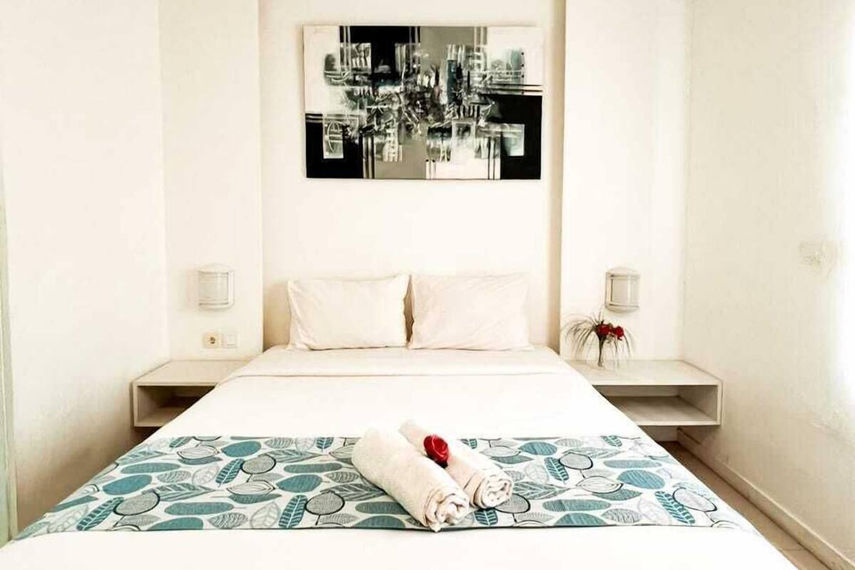 Une chambre d’hôtel comprenant un lit, deux tables de chevet, une œuvre d’art accrochée au mur et une couvre-lit à motifs.