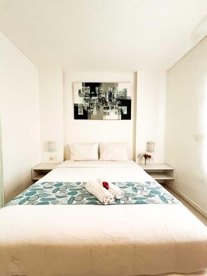 A hotel room with a bed, two bedside tables, a wall-mounted artwork, and a patterned bedspread. - Lacasa Senggigi By Royal Amreetha (Senggigi)