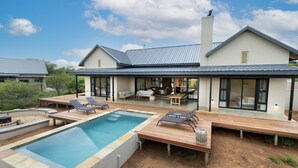 Een modern huis met een zwembad, tuinmeubilair en een patio.