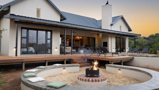 Een modern huis met een groot terras, buitenmeubels en een vuurplaats.