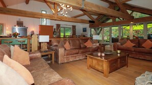 A spacious living area with wooden beams, leather sofas, and a wooden coffee table. - Kerslake House (Torpoint)