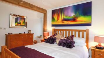 A bedroom with a wooden bed, a nightstand, a dresser, and a large painting of a colorful aurora borealis.