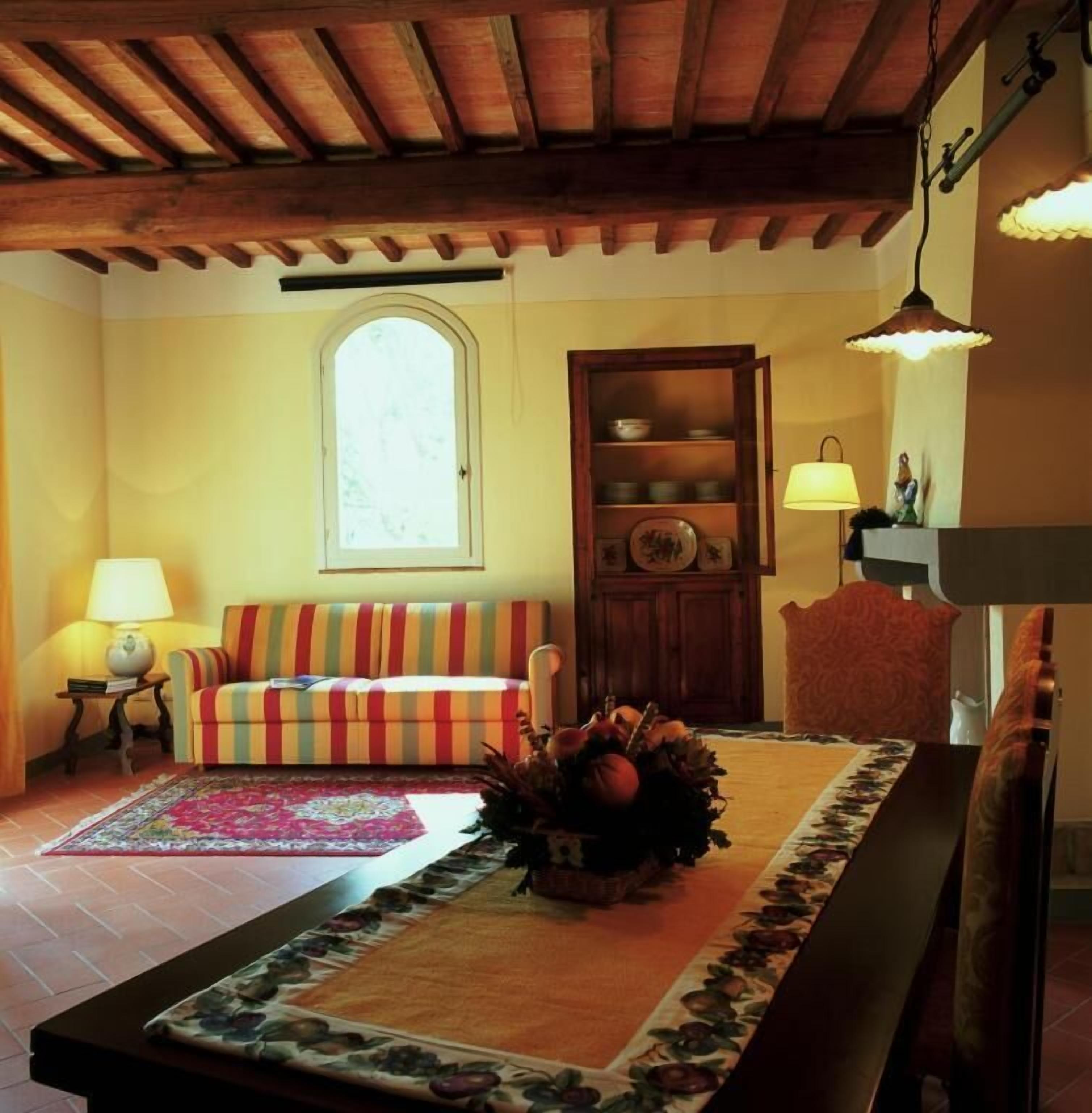 A cozy living room with a striped sofa, a wooden cabinet, and a floral table runner.
