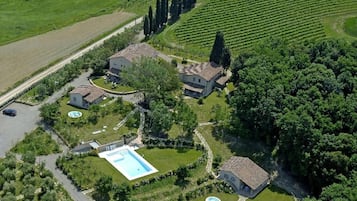 A large estate with multiple buildings, a swimming pool, and vineyard fields.