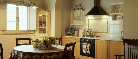 Una cocina acogedora con techo abovedado, una mesa de comedor con sillas y una lámpara colgante.