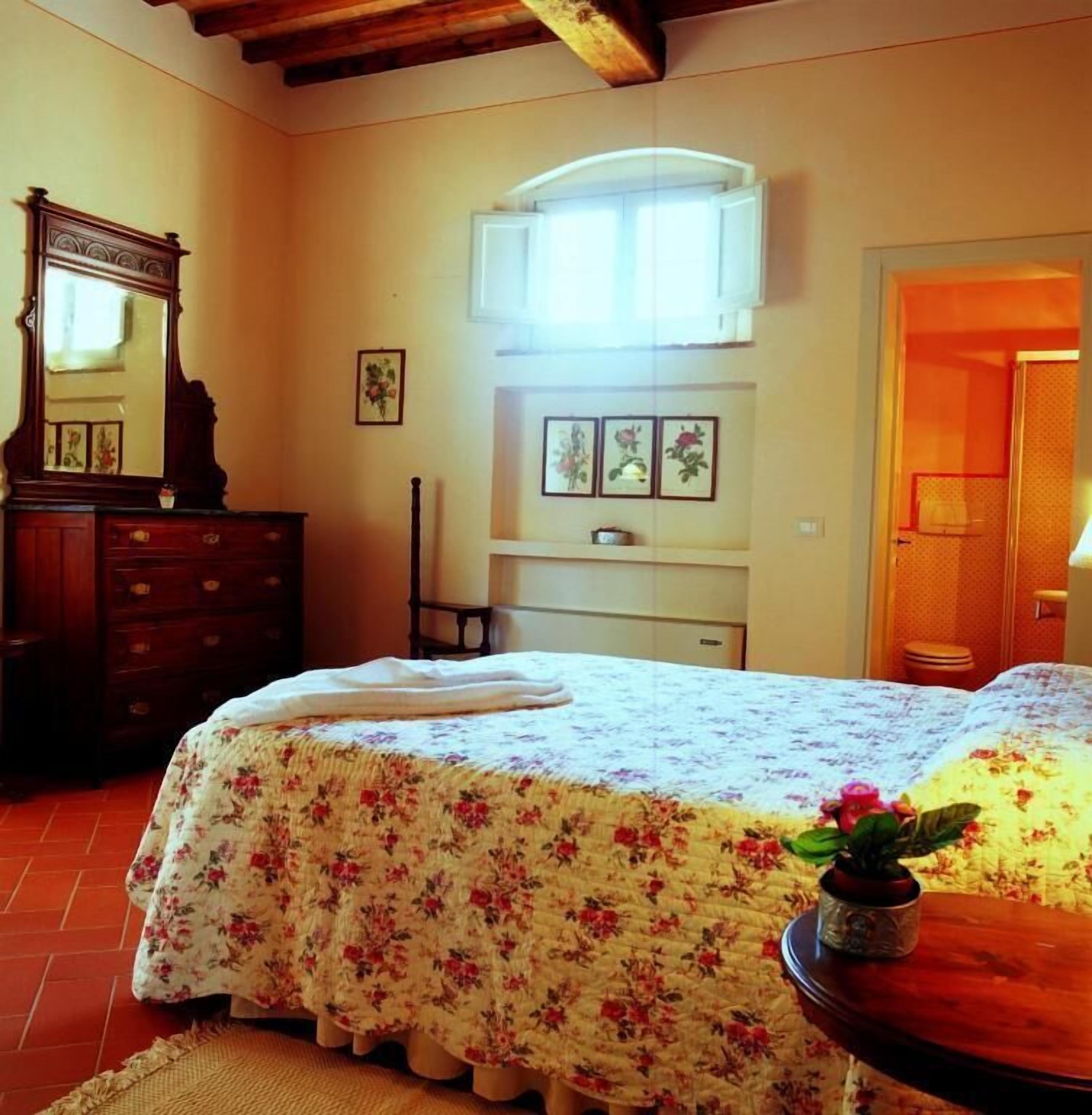 A bedroom with a bed, dresser, and a window with curtains.