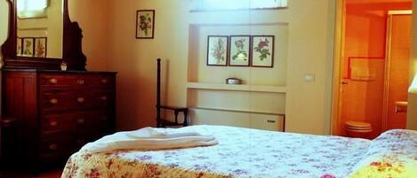 A bedroom with a bed, dresser, and a window with curtains.
