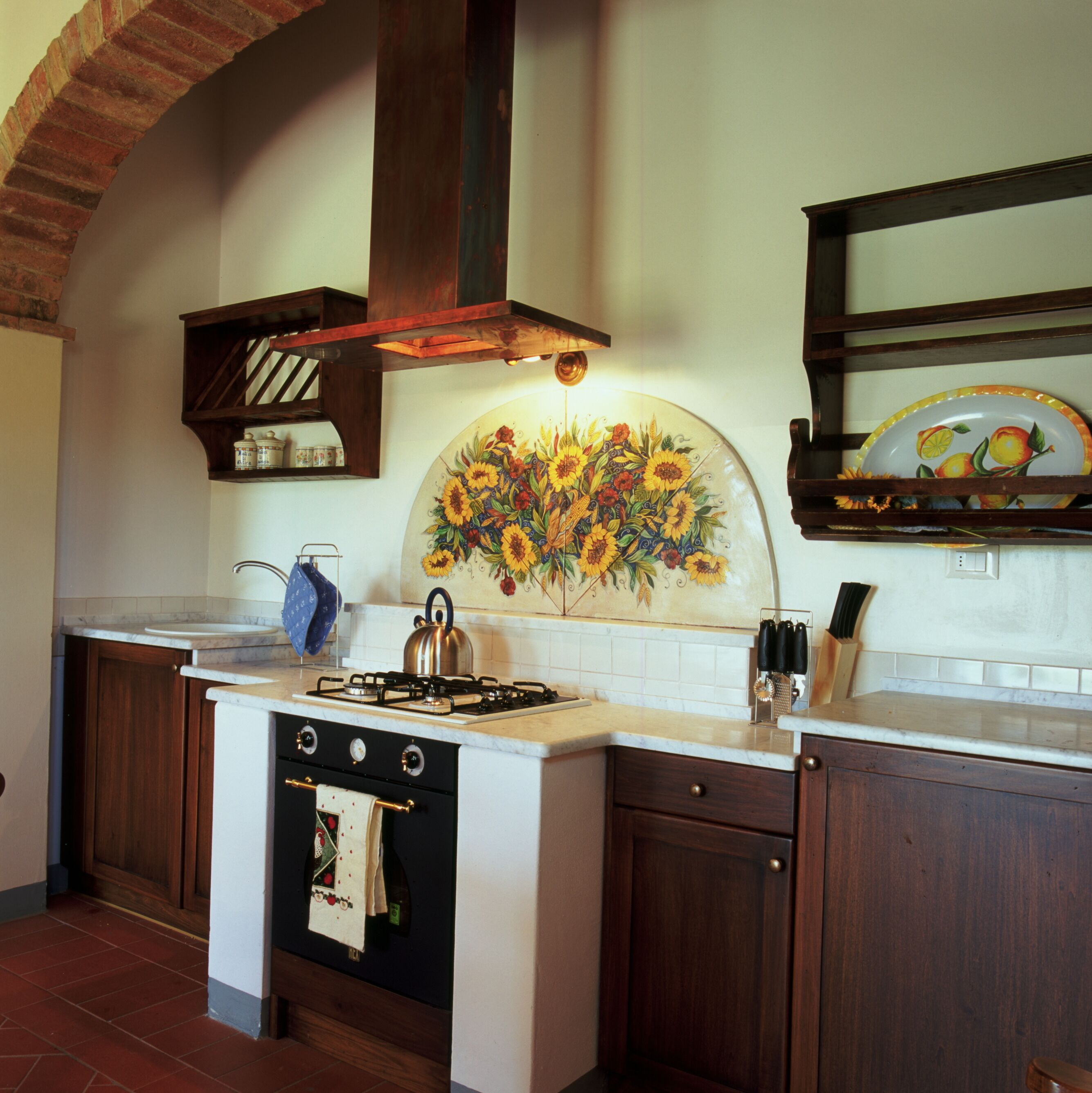 Una cocina con estufa, horno y un mural decorativo.