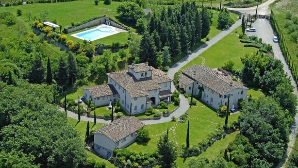 Un vaste domaine comprenant trois bâtiments principaux, une piscine et des jardins bien entretenus.