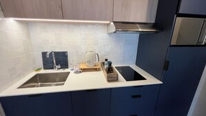 A modern kitchen with a white countertop, two sinks, a stainless steel range hood, and dark blue cabinets.