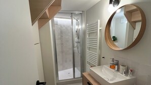 A modern bathroom with a wooden vanity, a large mirror, and a glass shower enclosure.