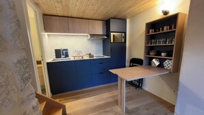 A compact kitchen with wooden cabinets, a built-in stove, and a shelf with kitchenware.