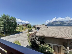 Ein Wohngebiet mit Häusern, einer asphaltierten Straße und Bergen im Hintergrund.