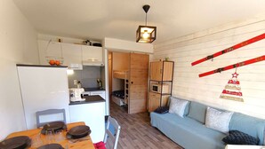 A compact living space with a kitchenette, a dining area, a sofa, and a ski-themed decoration. - Studio Cabin for 4 in Vielle Aure with Parking (Vielle-Aure)