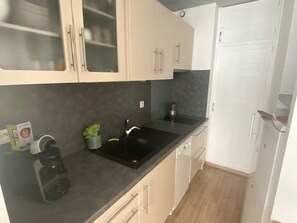 Una cocina moderna con armarios de colores claros, una encimera negra y una estufa empotrada.